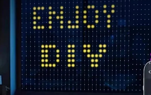 Photo de la fenêtre la nuit : le rideau LED affiche le message « ENJOY DIY » en pixels jaunes